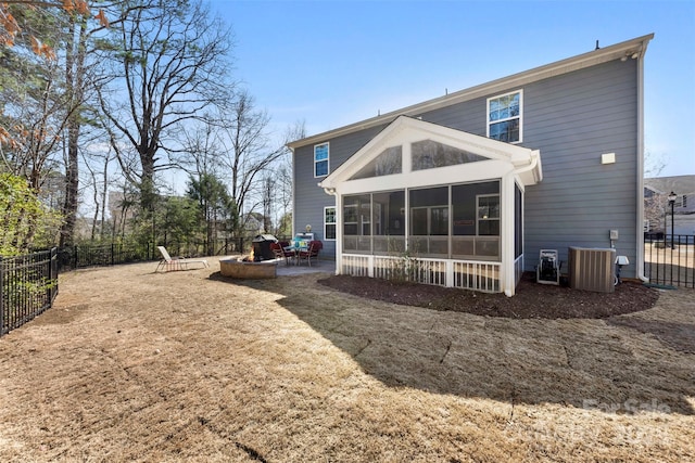 back of property featuring central air condition unit, an outdoor fire pit, a fenced backyard, and a sunroom