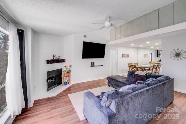 living room with a fireplace with flush hearth, wood finished floors, a ceiling fan, and vaulted ceiling