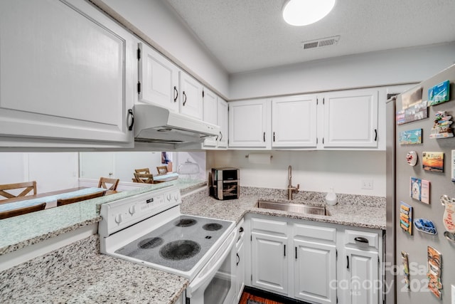 kitchen featuring visible vents, freestanding refrigerator, a sink, under cabinet range hood, and white electric range