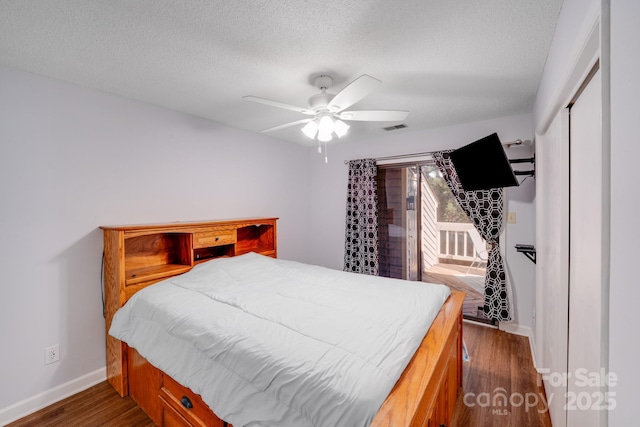 bedroom with visible vents, baseboards, dark wood-type flooring, and a textured ceiling