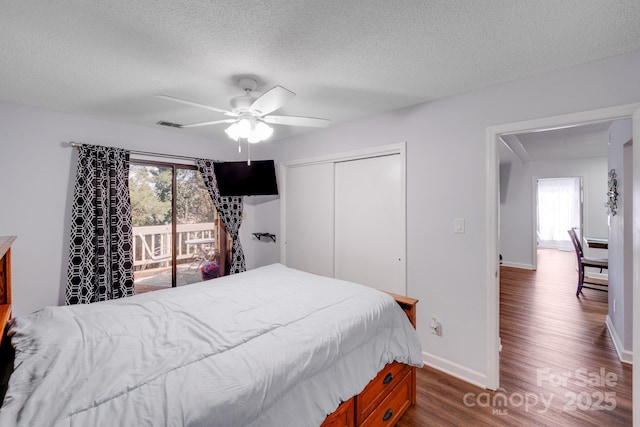 bedroom featuring a closet, multiple windows, a textured ceiling, and dark wood-type flooring