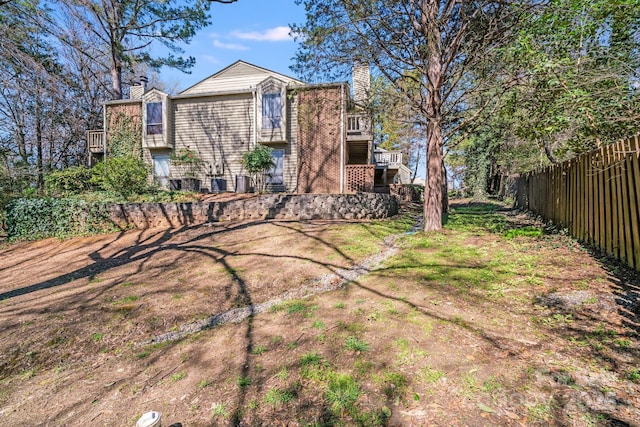 back of property with stairs, a balcony, fence, and a chimney