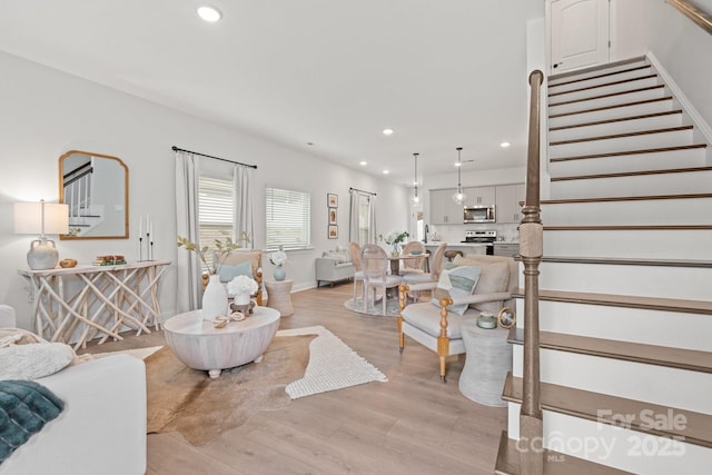 living area featuring recessed lighting, baseboards, light wood-style flooring, and stairs