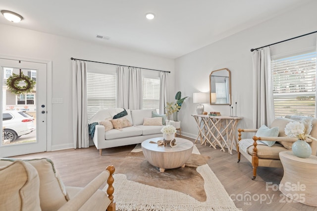 living area with a wealth of natural light, visible vents, and light wood finished floors
