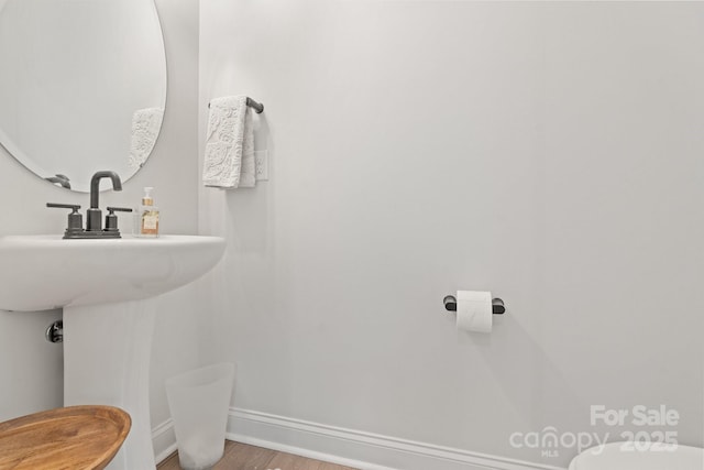half bathroom featuring toilet, baseboards, and wood finished floors