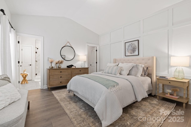 bedroom featuring lofted ceiling, a decorative wall, and wood finished floors