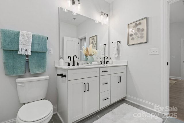 full bath with double vanity, toilet, baseboards, and a sink