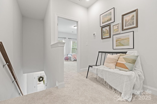 hall featuring baseboards, an upstairs landing, and carpet floors