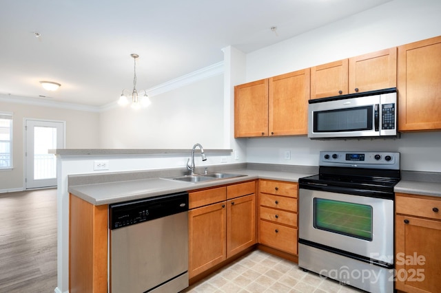 kitchen featuring a peninsula, a sink, stainless steel appliances, crown molding, and decorative light fixtures