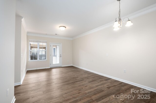 unfurnished room with crown molding, a notable chandelier, dark wood-style floors, and baseboards