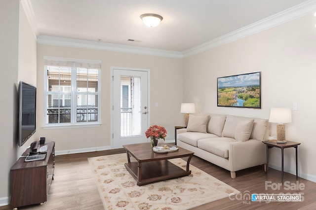 living area with visible vents, wood finished floors, a healthy amount of sunlight, and ornamental molding