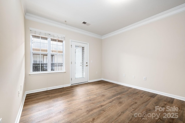 unfurnished room with visible vents, baseboards, wood finished floors, and ornamental molding