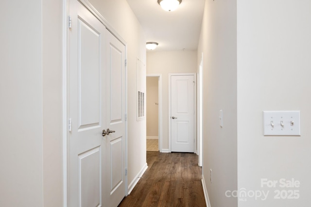 hall with dark wood-type flooring and baseboards