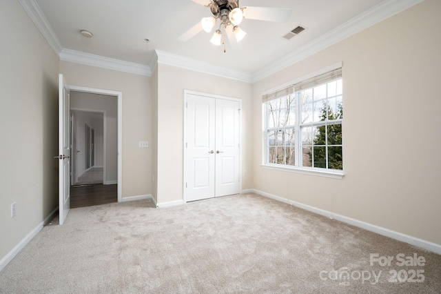 unfurnished bedroom featuring baseboards, visible vents, a closet, crown molding, and carpet flooring
