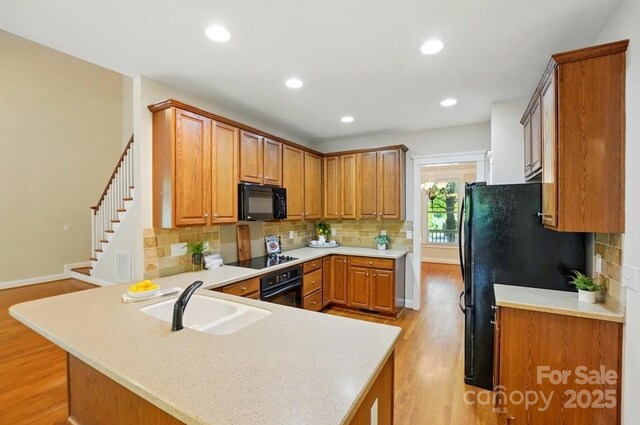 8008 Battersea Ct, Waxhaw, NC 28173 - kitchen featuring light wood-style flooring, a peninsula, a sink, and black appliances