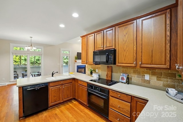 8008 Battersea Ct, Waxhaw, NC 28173 - kitchen featuring light wood-style flooring, a peninsula, a sink, and black appliances