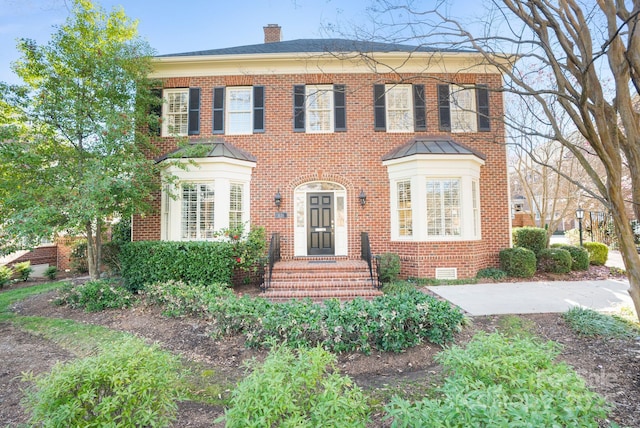 view of front of home with brick siding and a chimney