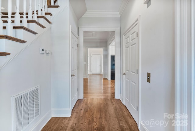 hall with stairway, wood finished floors, visible vents, baseboards, and crown molding