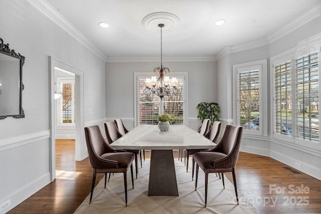 dining area with a chandelier, visible vents, ornamental molding, and wood finished floors