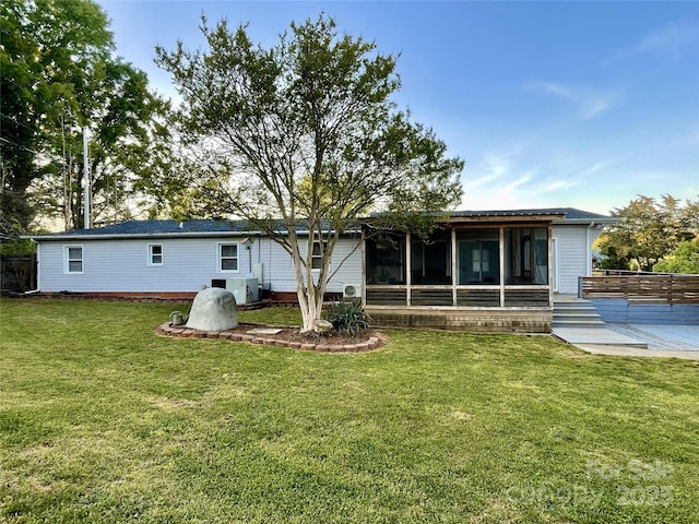 back of house featuring fence, a lawn, and a sunroom