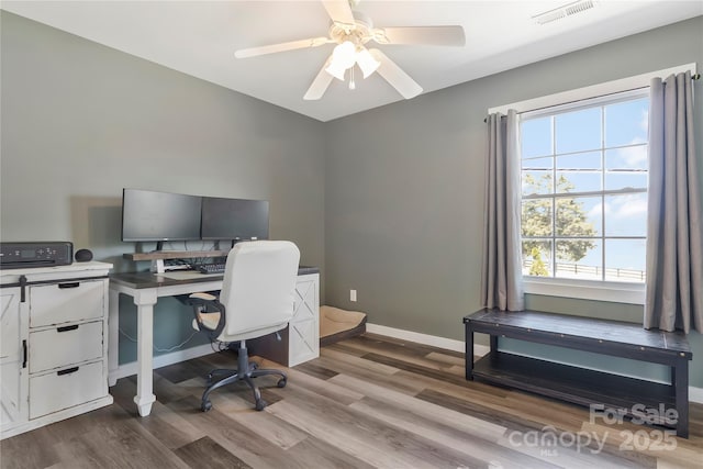 office area with wood finished floors, visible vents, a ceiling fan, and baseboards