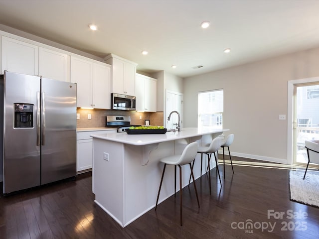 1814 Shumard Ln, Charlotte, NC 28205 - kitchen with a center island with sink, backsplash, appliances with stainless steel finishes, white cabinets, and dark wood-style flooring