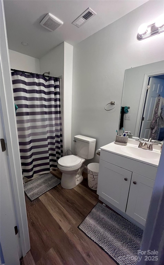 bathroom featuring visible vents, toilet, wood finished floors, and vanity