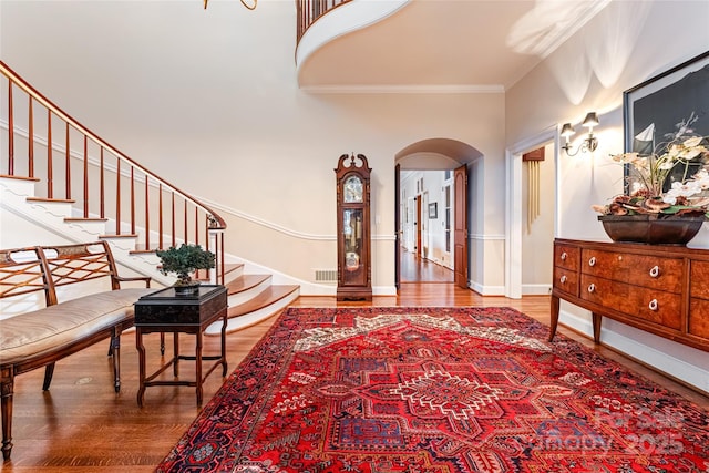 entryway featuring baseboards, ornamental molding, stairway, arched walkways, and wood finished floors