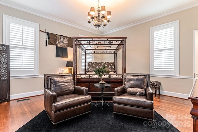 living area with ornamental molding, visible vents, hardwood / wood-style floors, baseboards, and a notable chandelier