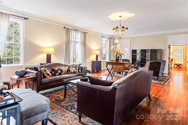 living room with ornamental molding, wood-type flooring, and an inviting chandelier