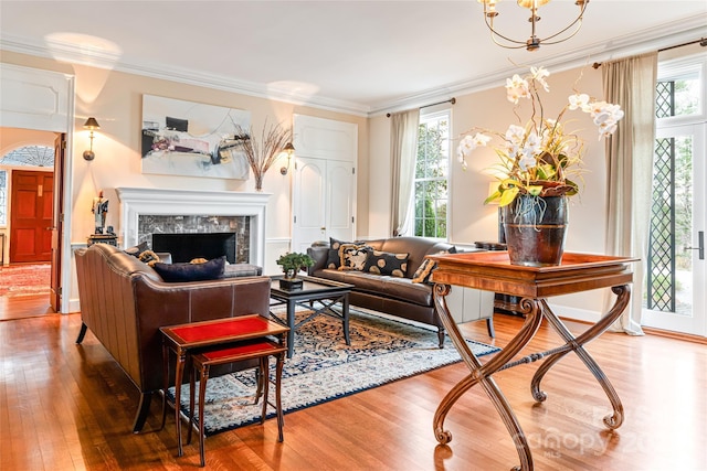 living room with a chandelier, ornamental molding, hardwood / wood-style floors, and a premium fireplace