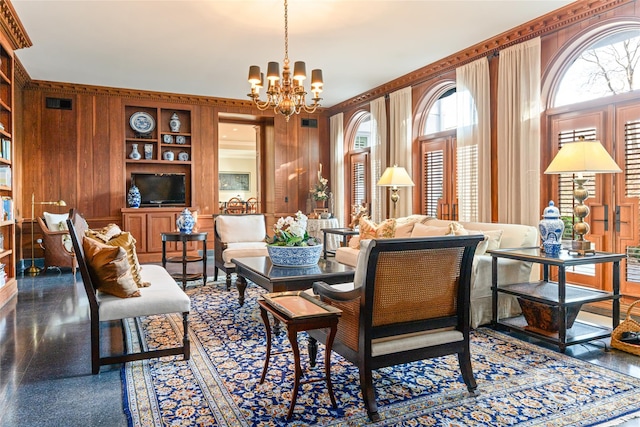 living area featuring wood walls, an inviting chandelier, built in shelves, and visible vents