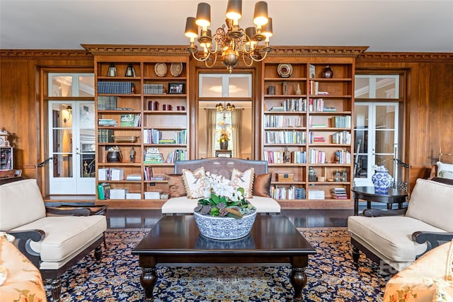 living area with wooden walls, built in features, an inviting chandelier, and wood finished floors