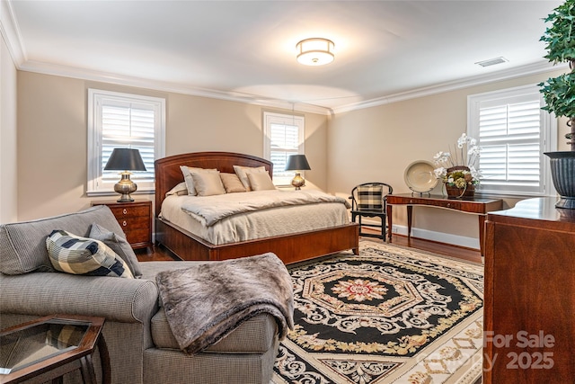bedroom with visible vents, baseboards, ornamental molding, and wood finished floors