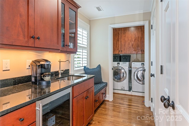 clothes washing area with washer and dryer, a sink, ornamental molding, laundry area, and wine cooler