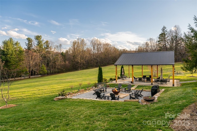 view of property's community with a lawn, a gazebo, a patio area, and an outdoor fire pit