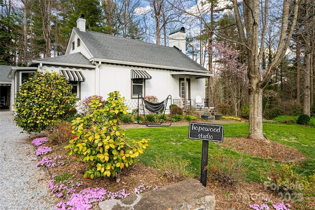 view of front of home featuring a front yard, a shingled roof, and a chimney