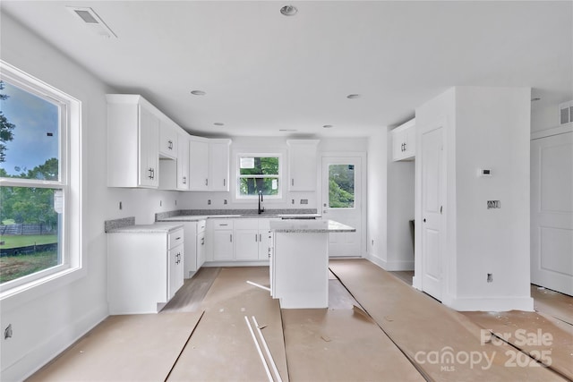 513 Harrel St, Salisbury, NC 28144 - kitchen featuring a sink, baseboards, white cabinets, and a center island