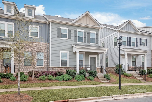 townhome / multi-family property featuring stone siding, board and batten siding, and a porch