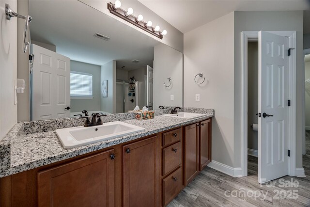 10071 Highland Creek Cir, Indian Land, SC 29707 - bathroom featuring a sink, visible vents, double vanity, and wood finished floors