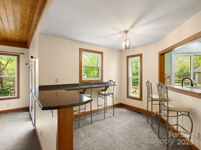 9009 Stourbridge Dr, Huntersville, NC 28078 - kitchen with carpet, baseboards, a breakfast bar, a peninsula, and wooden ceiling