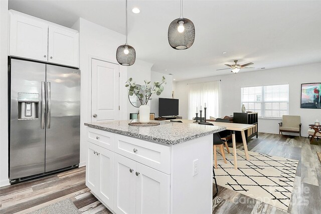 kitchen featuring a kitchen island, light wood-style floors, stainless steel refrigerator with ice dispenser, white cabinetry, and a ceiling fan