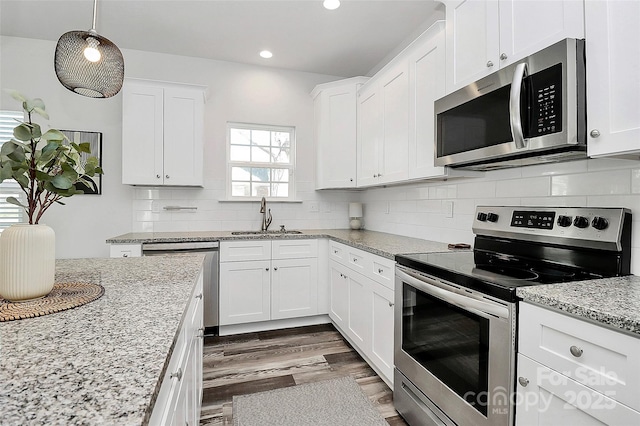 kitchen with white cabinetry, decorative backsplash, appliances with stainless steel finishes, and a sink