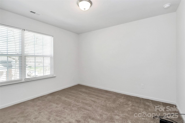 carpeted spare room featuring visible vents and baseboards