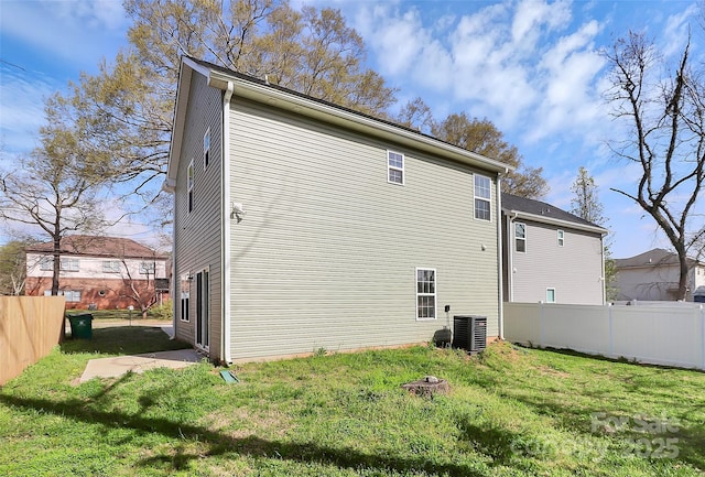 rear view of property with central air condition unit, a yard, and fence