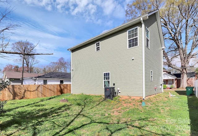back of property with cooling unit, a lawn, and fence