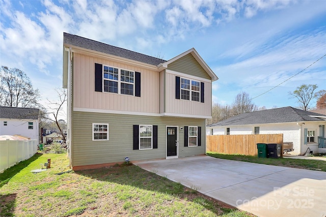 view of front of home featuring a front yard, concrete driveway, fence, and board and batten siding