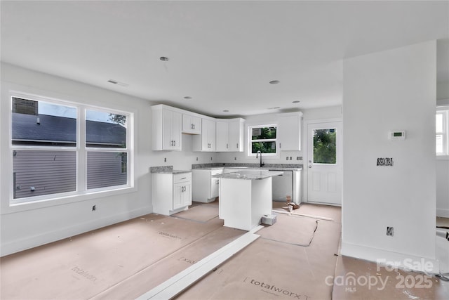 515 Harrel St, Salisbury, NC 28144 - kitchen with white cabinetry, a kitchen island, dishwasher, light stone counters, and baseboards