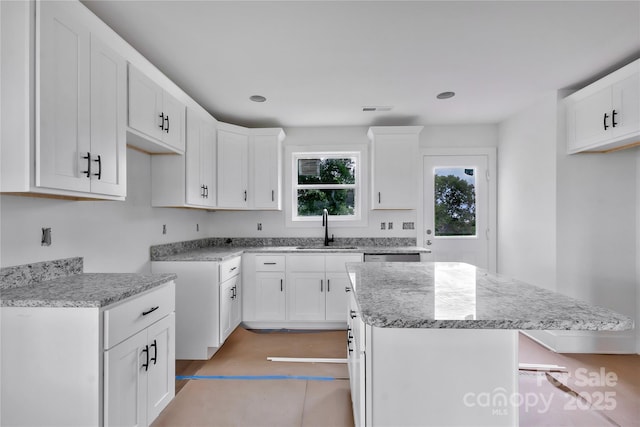 515 Harrel St, Salisbury, NC 28144 - kitchen with a sink, a kitchen island, light stone counters, white cabinets, and a kitchen breakfast bar