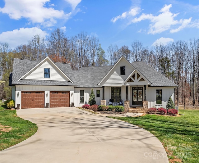 view of front of house featuring a front yard, french doors, concrete driveway, and roof with shingles